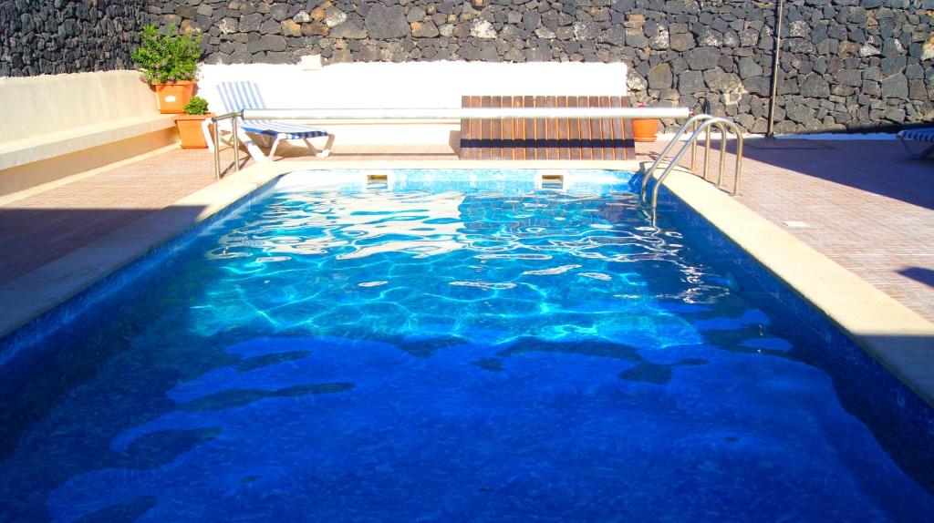 MozagaFinca la Rubina的一个带长凳和蓝色海水的游泳池