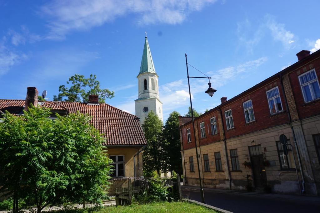 库尔迪加Pilskalnu hostelis的教堂,教堂的背景是陡峭的建筑物
