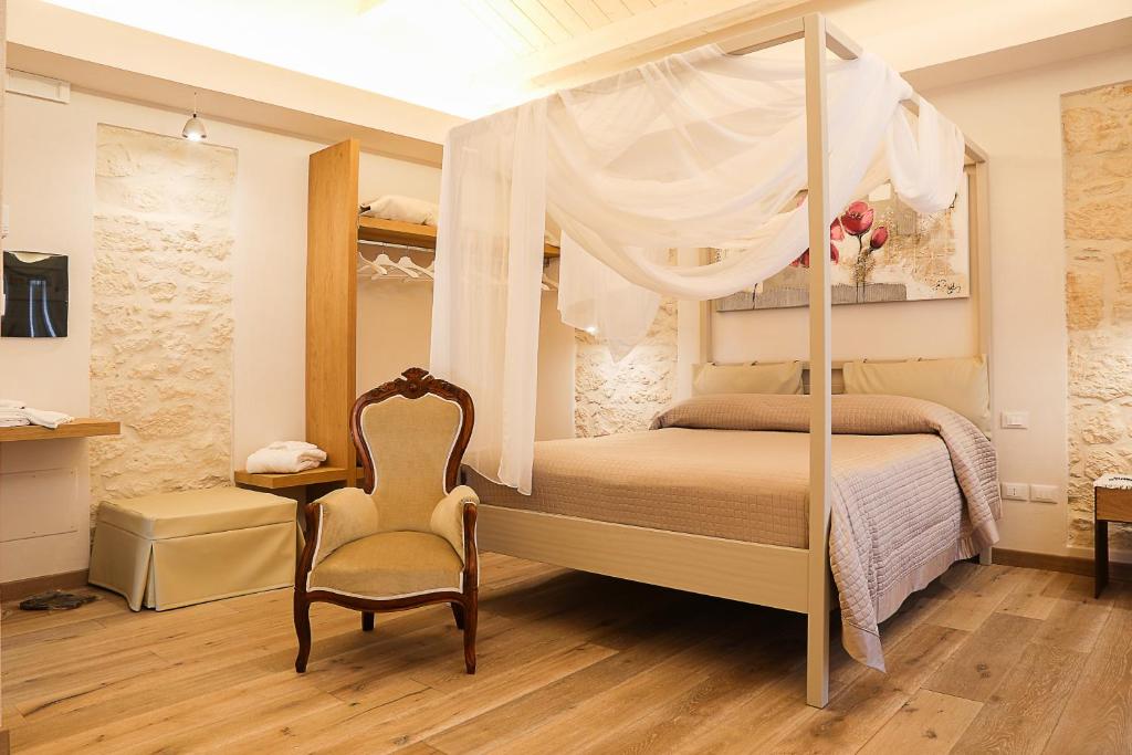 瓜尔迪亚格雷莱B&B Dei Raselli的一间卧室配有一张天蓬床、椅子和一张桌子