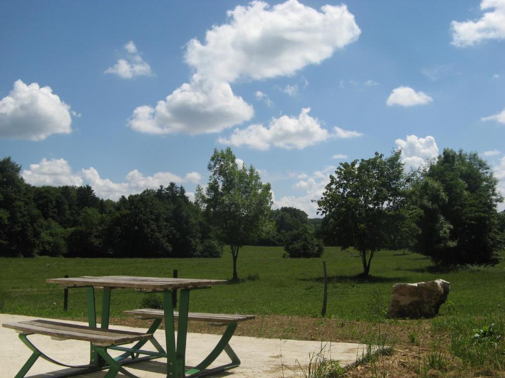 ArçonGite De La Distillerie的野餐桌和田野上的两把长椅
