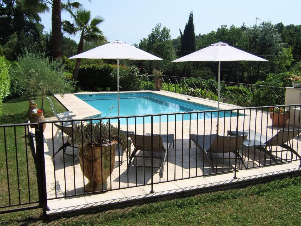 圣保罗-德旺斯AU VALLON ROUGE (Studio)的围栏旁带椅子和遮阳伞的游泳池