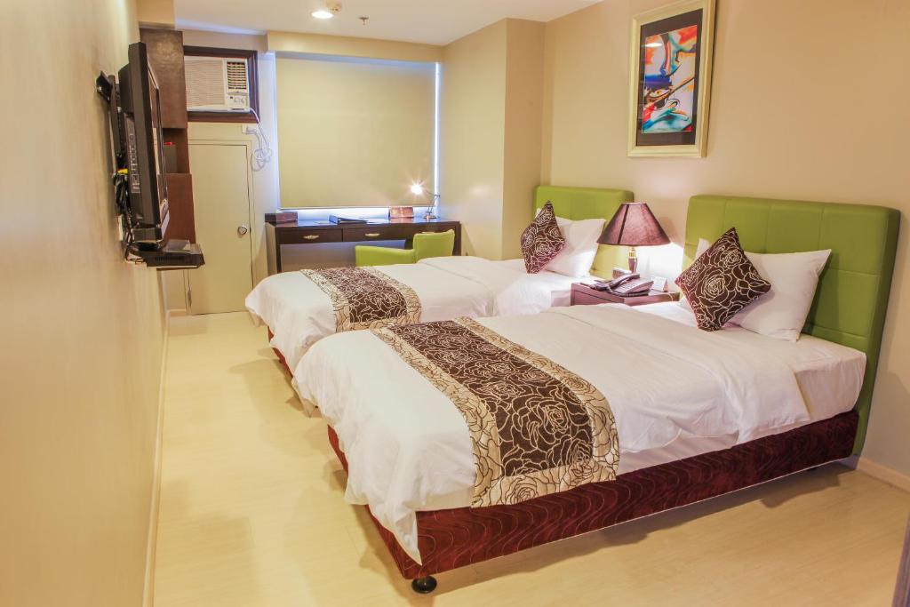 马尼拉The Exchange Regency Residence Hotel Managed by HII的酒店客房设有两张床和电视。