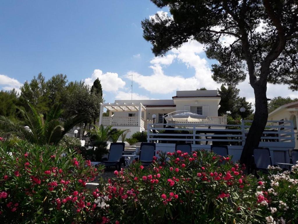 莱波拉诺Villa Satyria B&B的一座带椅子和鲜花的度假村,位于一座建筑前