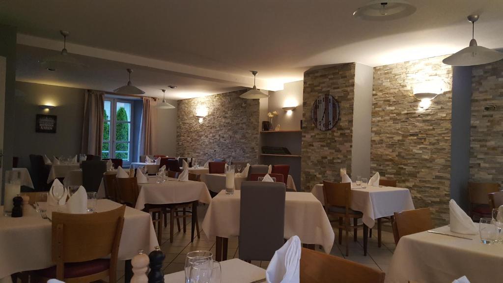 ApchonAuberge le Cheylet的一间设有白色桌椅和砖墙的餐厅
