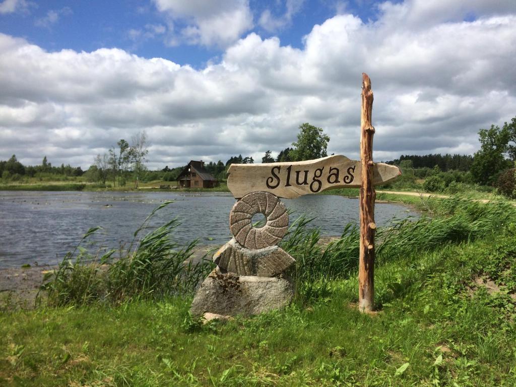LēnaBrīvdienu māja Slugas的坐在河边的草上的一个标志