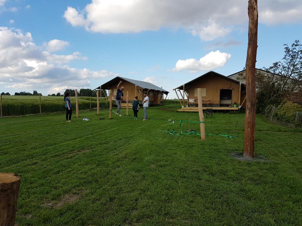 BeverenGlamping op het Zeugekot的一群人站在有小屋的田野里