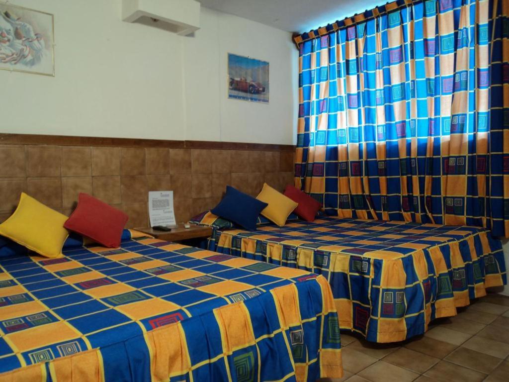 翡翠海岸Canadian Resort Veracruz的两张带色彩缤纷枕头的床
