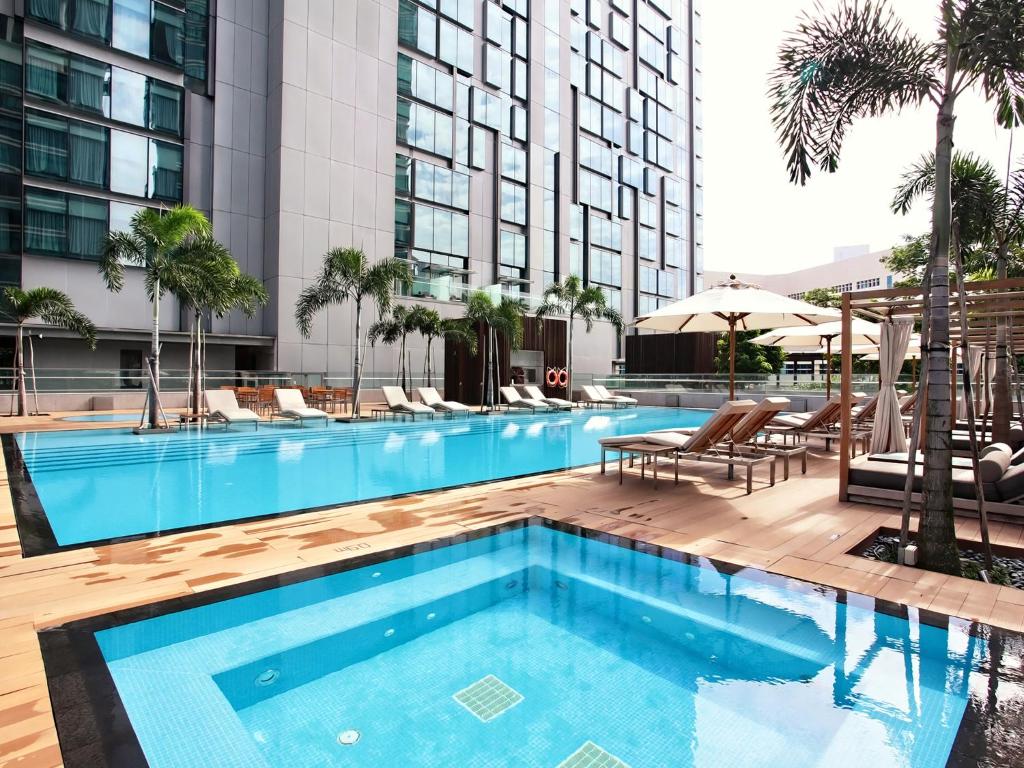 新加坡Oasia Hotel Novena, Singapore by Far East Hospitality的一座带桌椅的游泳池以及一座建筑