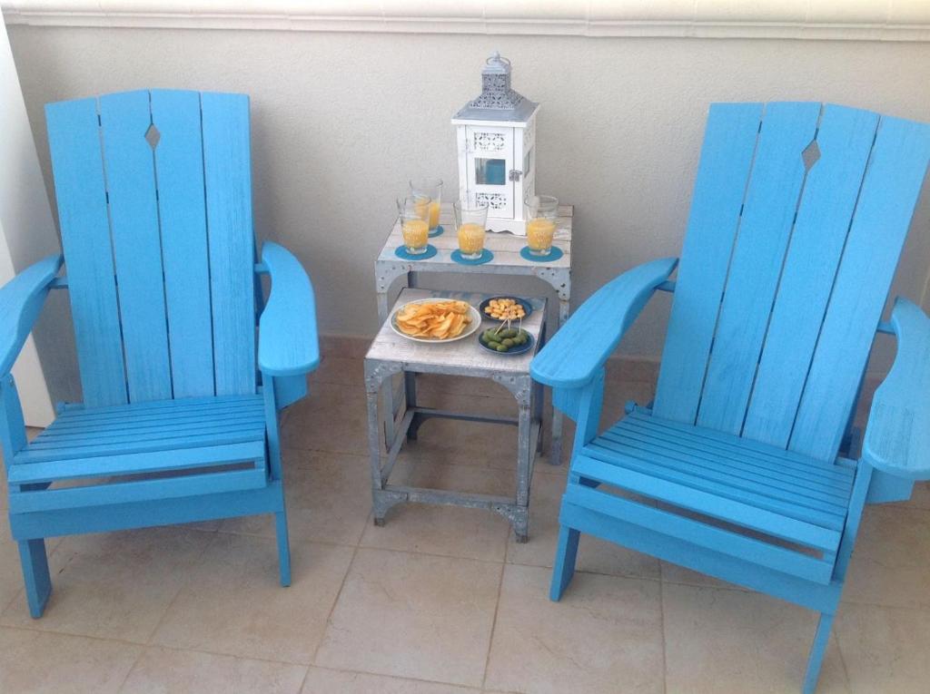 萨维勒特里Maricasa Savelletri的两张蓝色的椅子和一张桌子,上面有盘子的食物