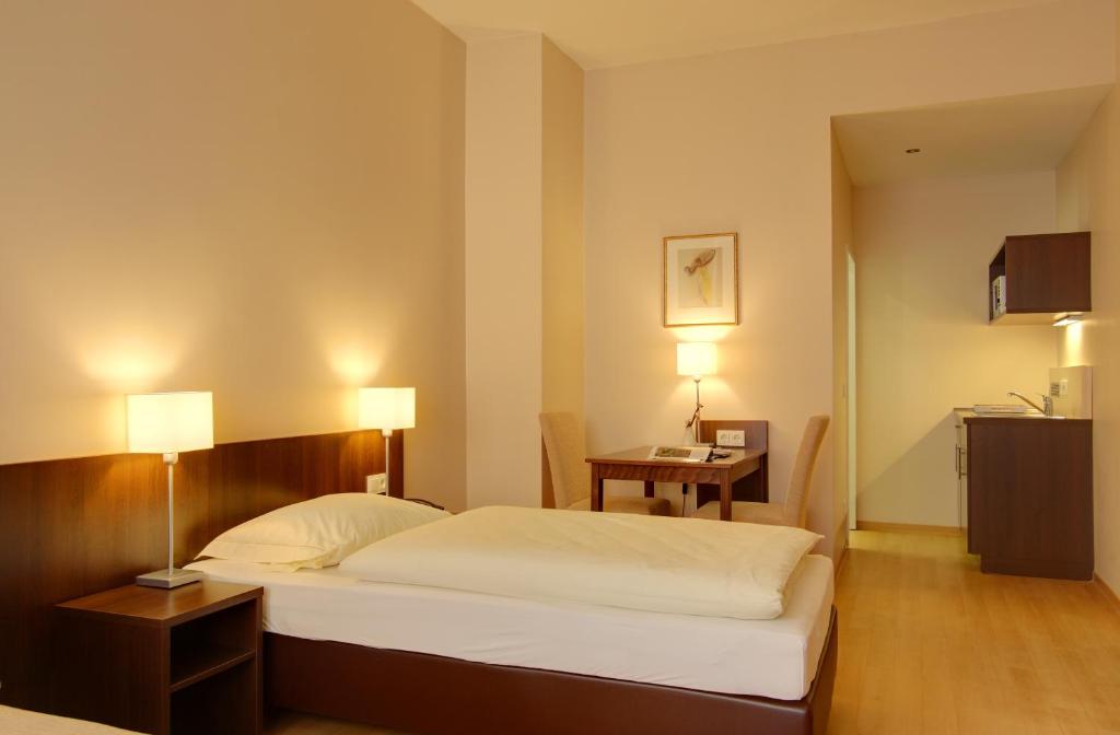 波恩梅塞德斯城市酒店的一间卧室配有一张床、一张桌子和两盏灯。