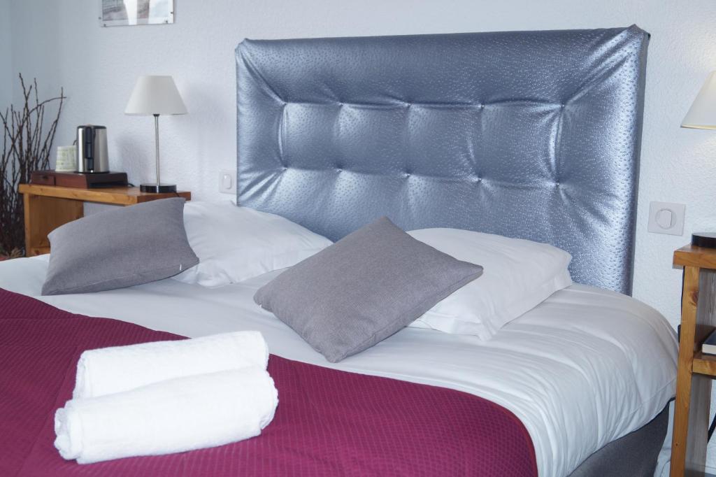 Hières-sur-Amby昂比河谷酒店的一张带皮革床头板和枕头的床