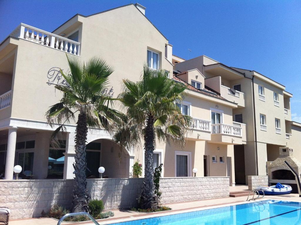 波弗加纳卡斯特尔别墅酒店的一座棕榈树环绕的建筑,位于游泳池前