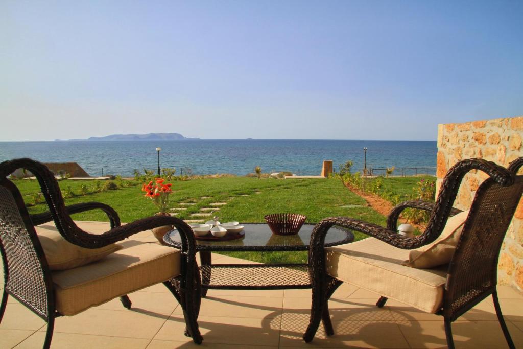古瓦伊Sea View Beachfront Villa Maria的一个带两把椅子和一张桌子的庭院和大海
