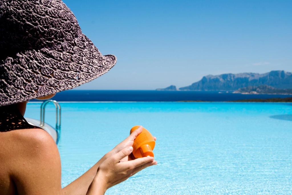 奥尔比亚Hotel Luna Lughente的戴着橙色的帽子的女人,在水边