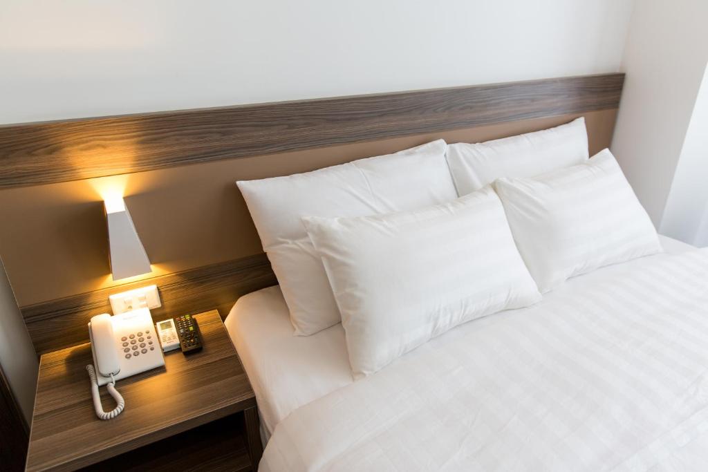 海防朋特酒店的一张带白色枕头的床和一张桌子上的电话