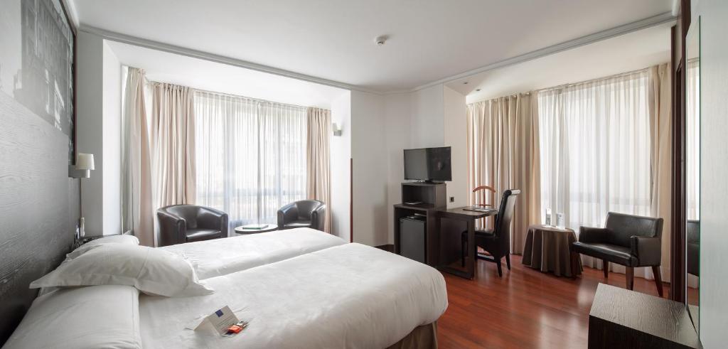 潘普洛纳尤尔迪酒店的酒店客房,配有一张床、一张桌子和椅子