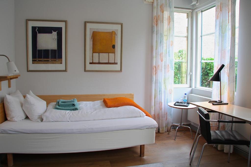 隆德奥斯卡酒店的一间卧室配有一张床、一张书桌和一个窗户。