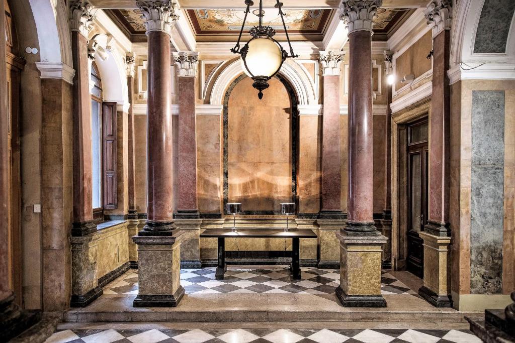 的里雅斯特七历史套房酒店的走廊上设有桌子,位于有柱子的建筑中