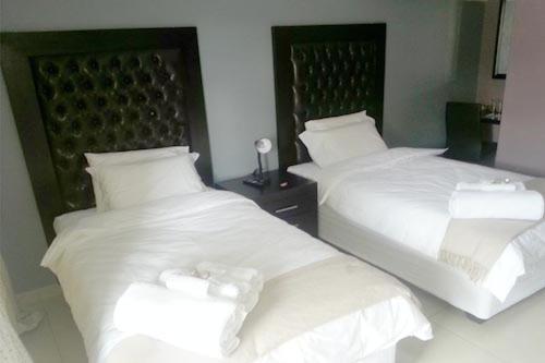 SibasaMasili Guesthouse & Conference的配有2张床的带白色床单和枕头的客房