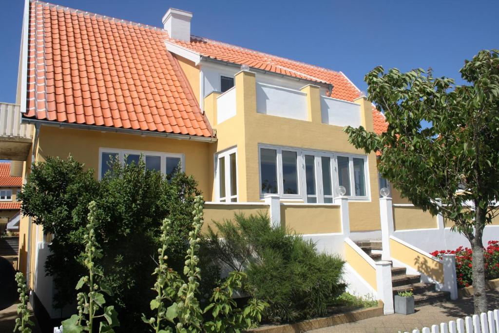 斯卡恩Østre Strandvej 49的黄色房子,有橙色屋顶