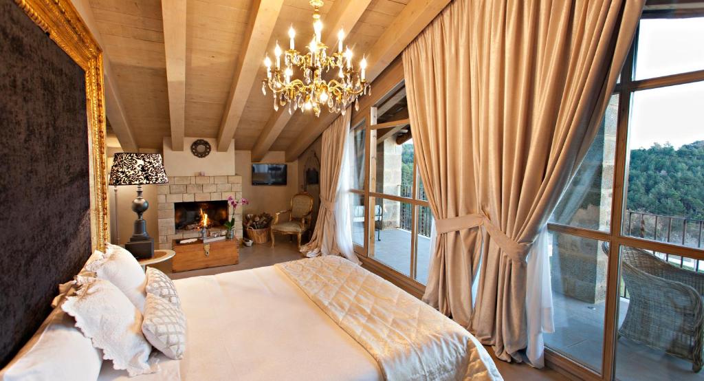 LladursLa Vella Farga Hotel的一间卧室配有一张床、一个壁炉和一个吊灯。