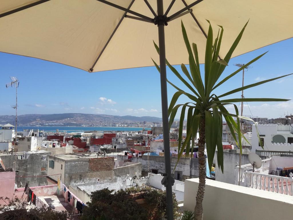 丹吉尔阿鲁斯卡梅尔摩洛哥传统庭院旅馆的阳台享有城市美景,配有遮阳伞。