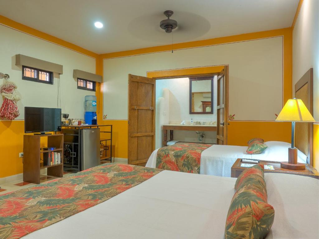 梅里达Hotel Luz en Yucatan的酒店客房设有两张床和电视。