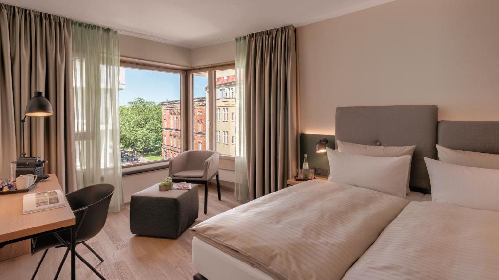柏林雅德酒店的配有一张床、一张书桌和一扇窗户的酒店客房