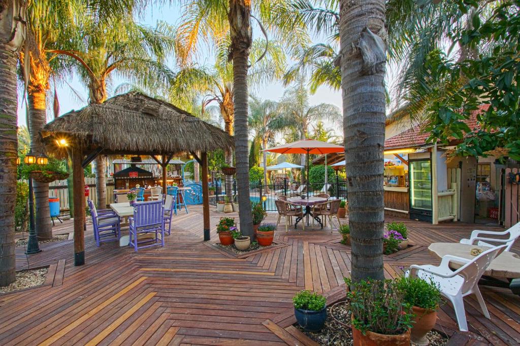 哈德内斯非洲风情度假酒店的一个带桌椅的木制甲板和棕榈树