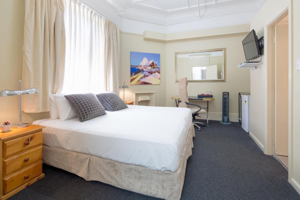 悉尼中立湾旅馆的一间卧室配有一张床、一张书桌和一个窗户。
