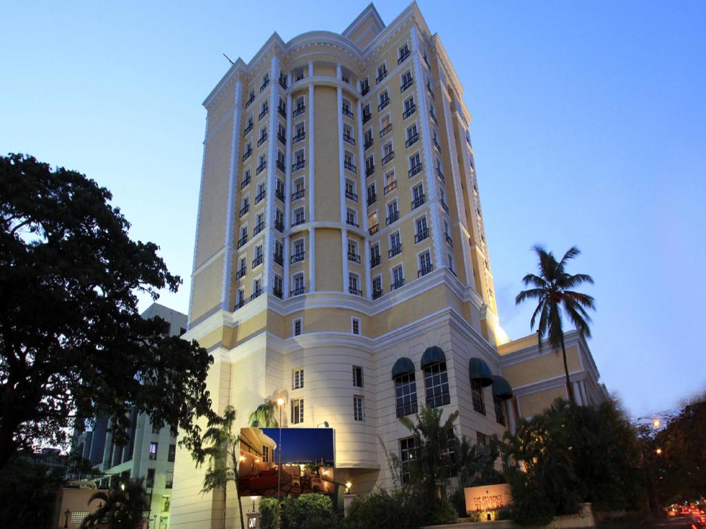 钦奈高塔酒店的一座白色的大建筑,前面有一棵棕榈树