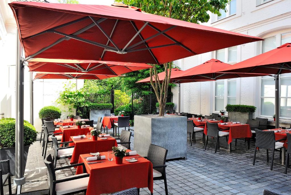 科特赖克梅塞恩酒店的一间设有红色桌椅和遮阳伞的餐厅
