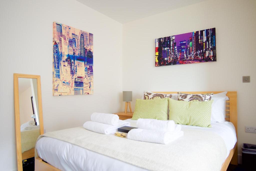 剑桥Signet Apartments - Ceres的卧室配有一张白色床,墙上挂有两幅画作