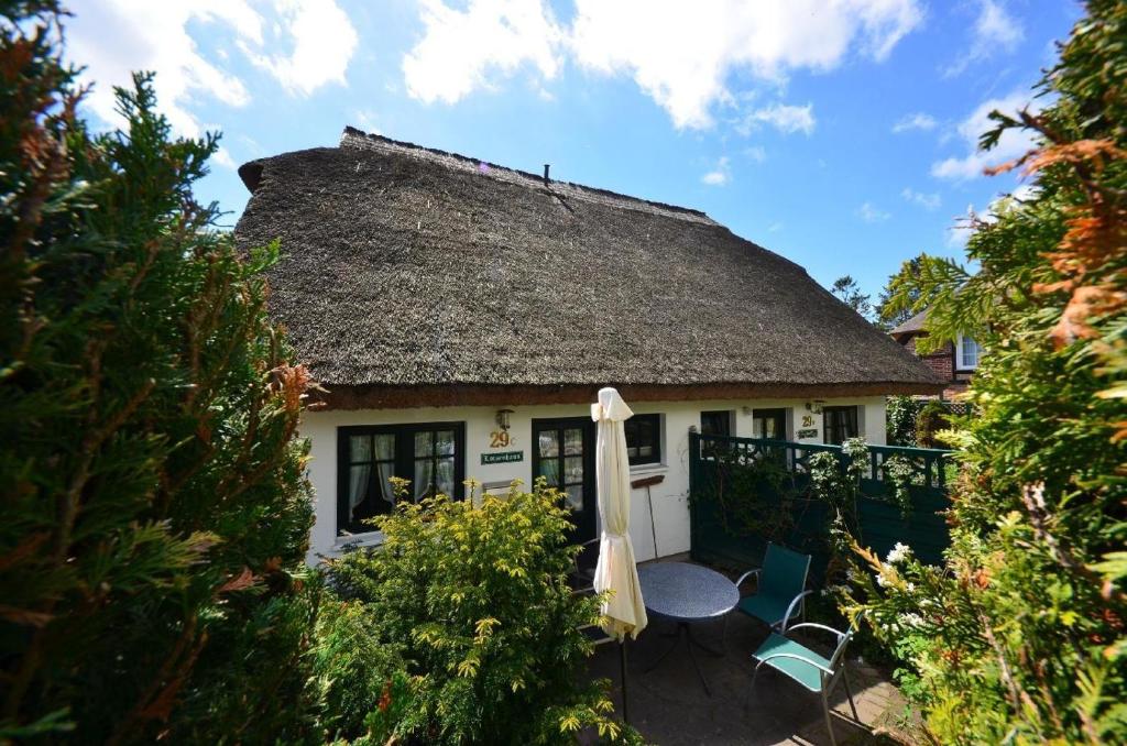 格罗斯齐克Lotsenhaus-in-Gross-Zicker-Halbinsel-Moenchgut的茅草屋顶房屋设有天井和遮阳伞