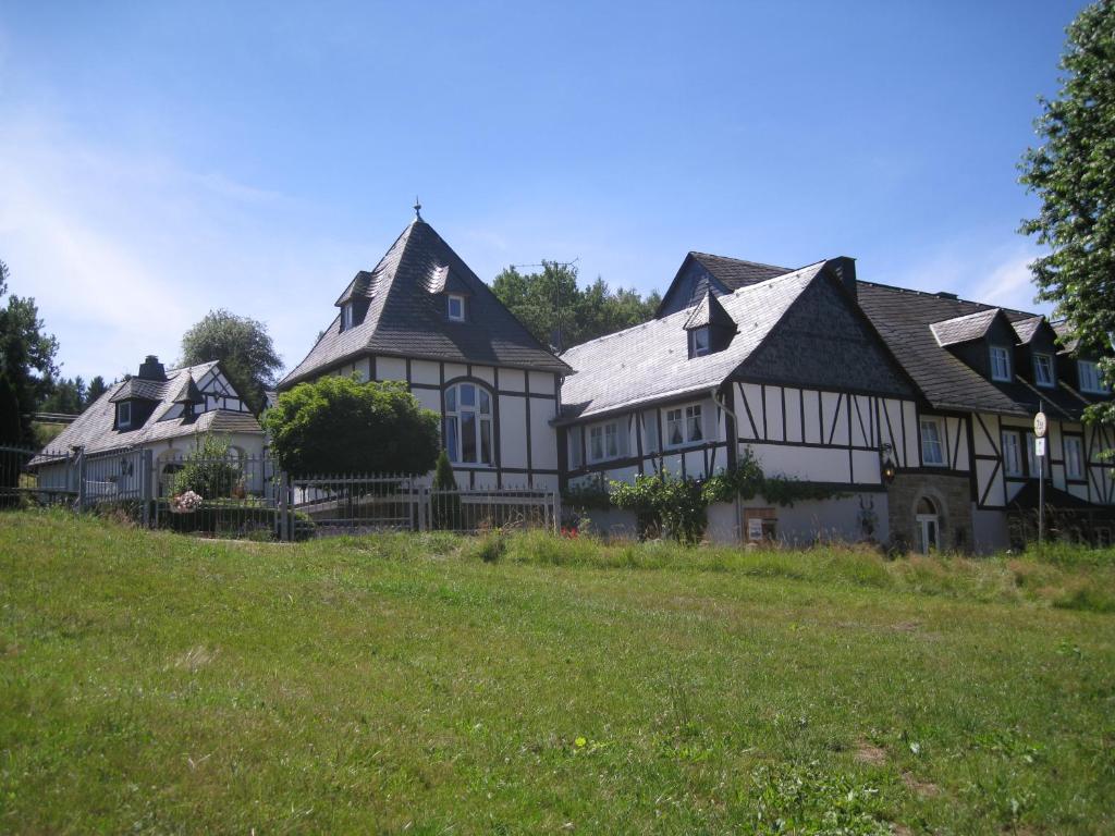 KrummenauRomantikmühle Heartlandranch的绿色田野上一座白色和黑色的大房子