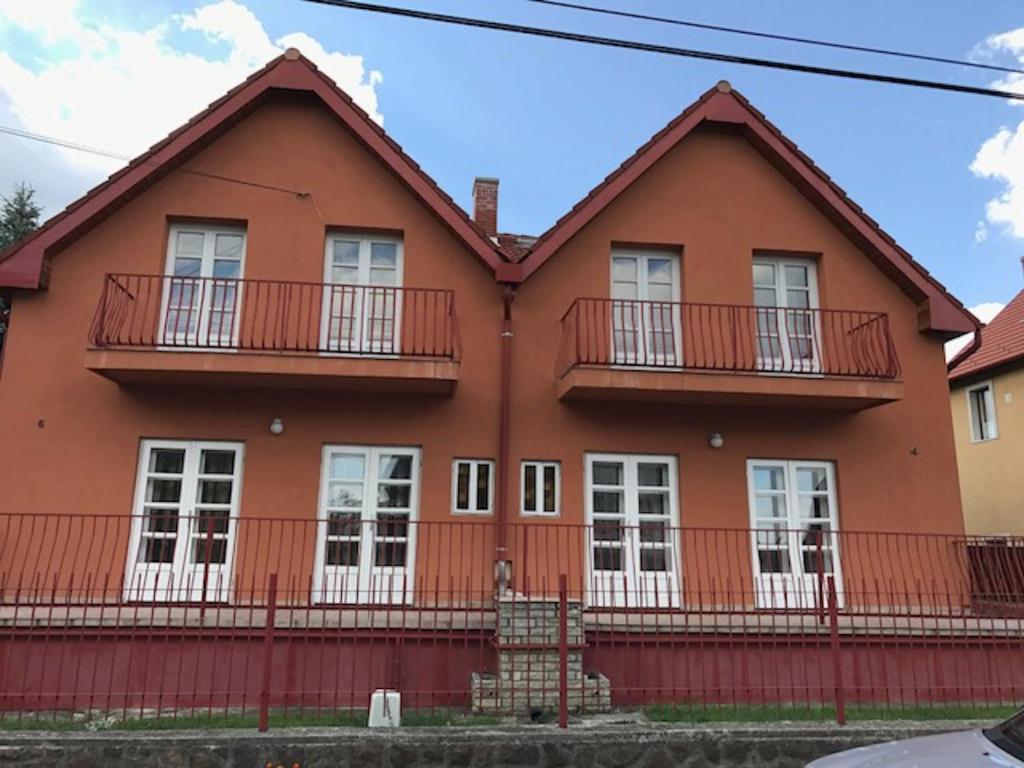 下厄尔什Barátság Ház的红色的房子,设有白色窗户和阳台