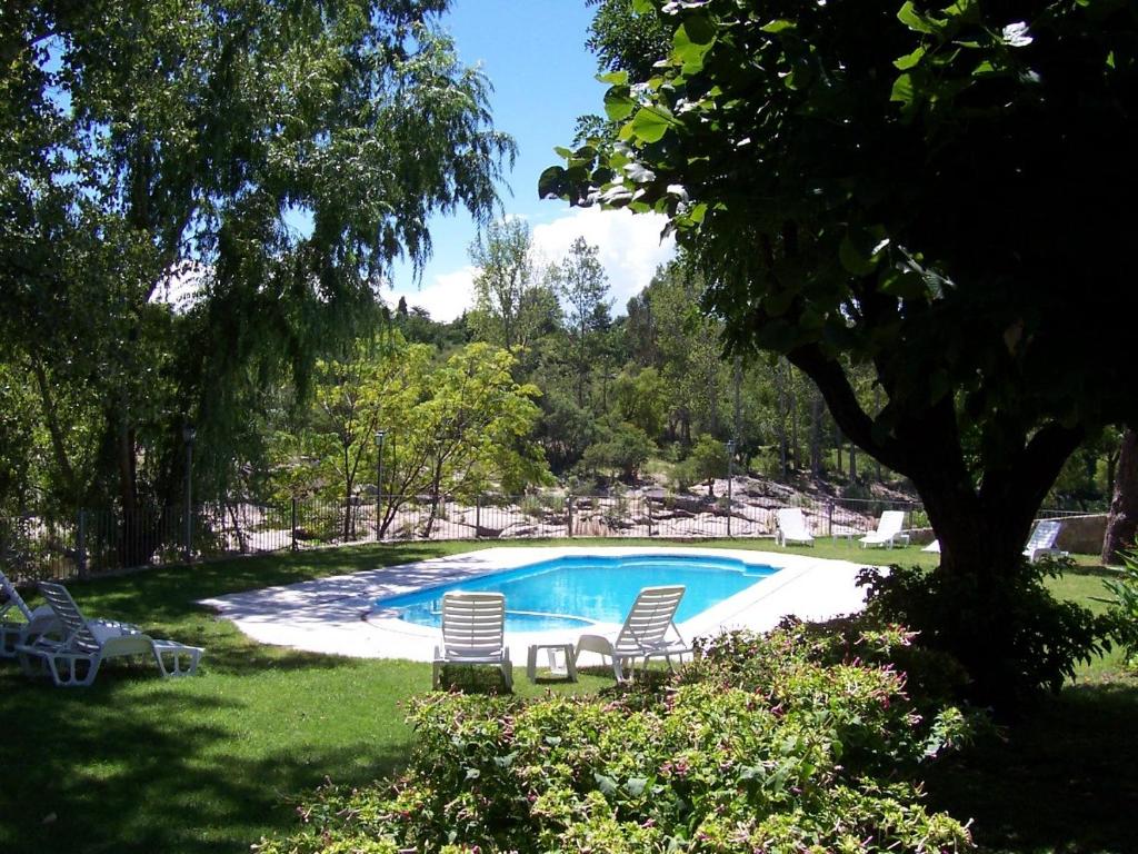 米娜克拉韦罗科斯塔塞拉纳公寓酒店的一个带两把椅子和一棵树的游泳池