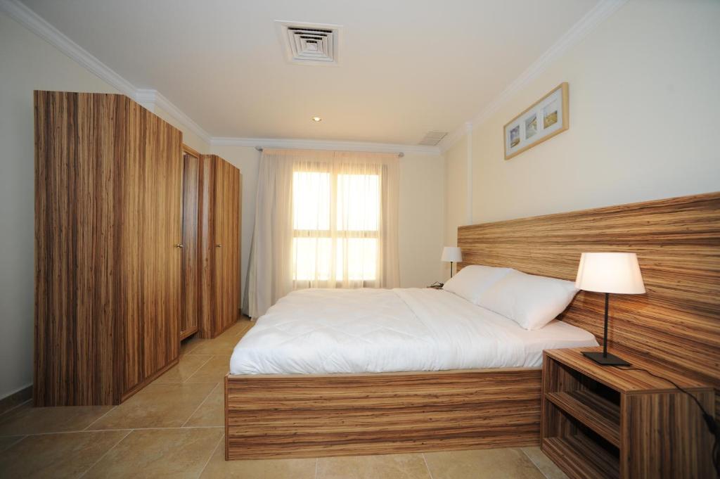 科威特莎米亚带露台家具的公寓的一间卧室配有一张大床和木制床头板
