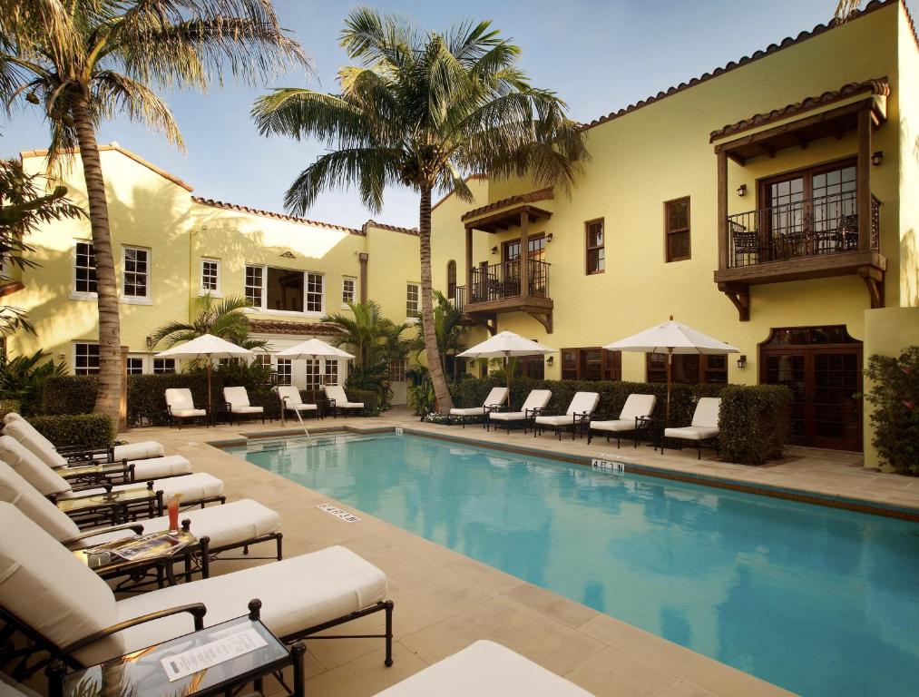 棕榈滩巴西苑酒店的一个带躺椅的度假村游泳池,并种植了棕榈树
