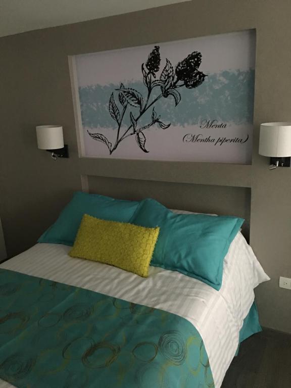 普埃布拉Herbal Inn Suites的一间卧室配有一张带蓝色和绿色枕头的床