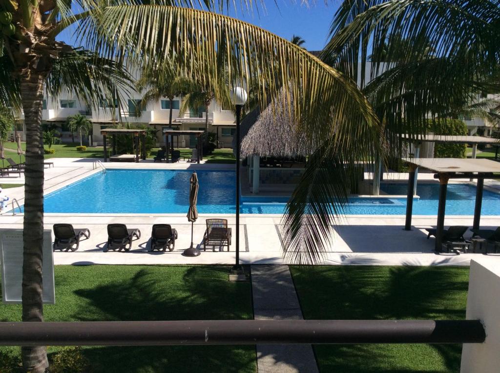 阿卡普尔科Villa Perfecta Zona Diamante的一个带椅子和桌子的游泳池以及棕榈树