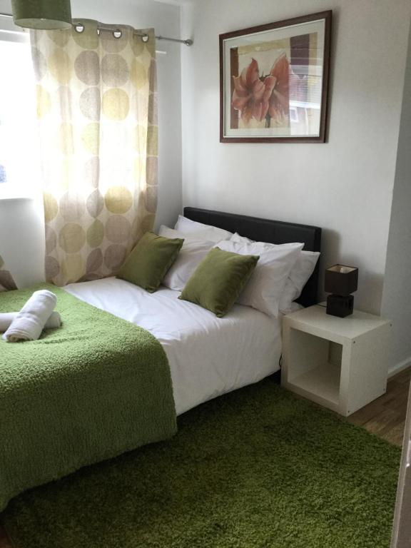 巴塞尔顿4 Bed House next to Basildon Town Centre的卧室配有带绿色枕头的大型白色床
