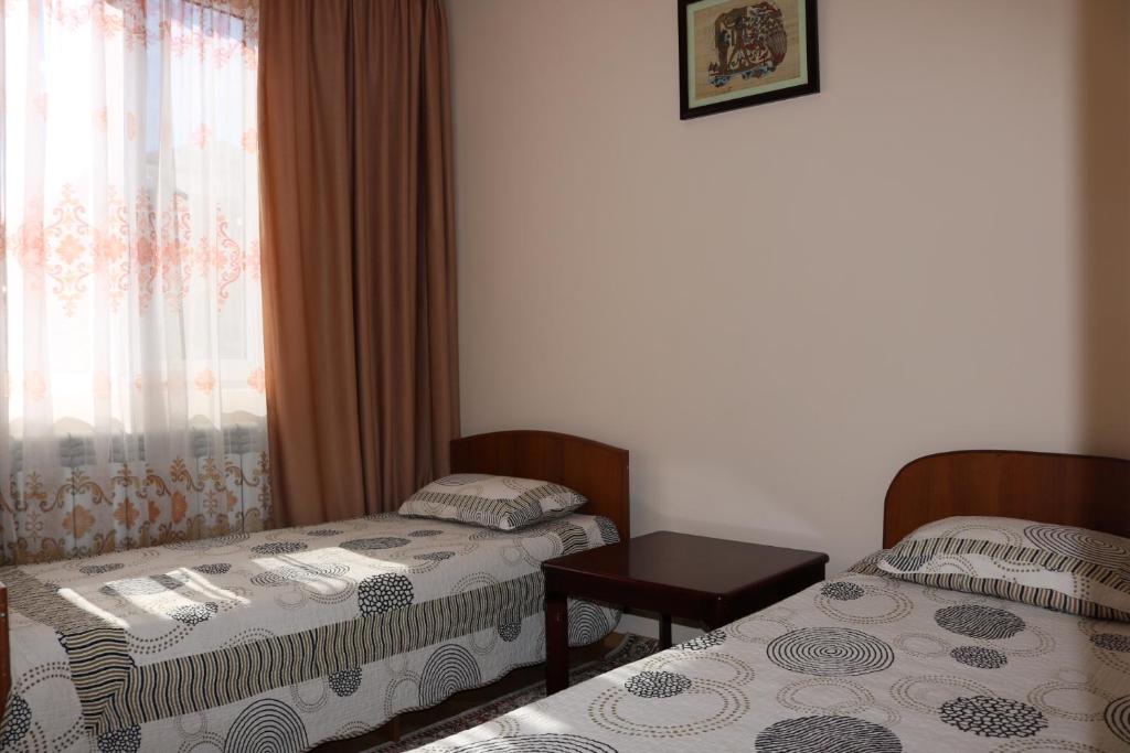 乔尔蓬阿塔Гостевой дом "Kalinka"的客房设有两张床、一张桌子和一扇窗户。