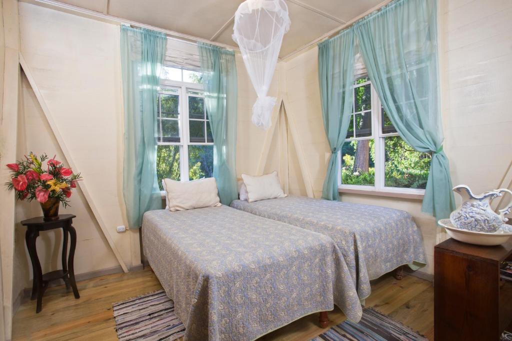 NewcastleBarbecue Heritage Gardens Cottage - JM的一间卧室设有两张床和两个窗户。