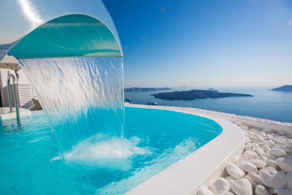 菲罗斯特法尼圣托里尼别致酒店的水喷泉,在有海洋背景的游泳池里