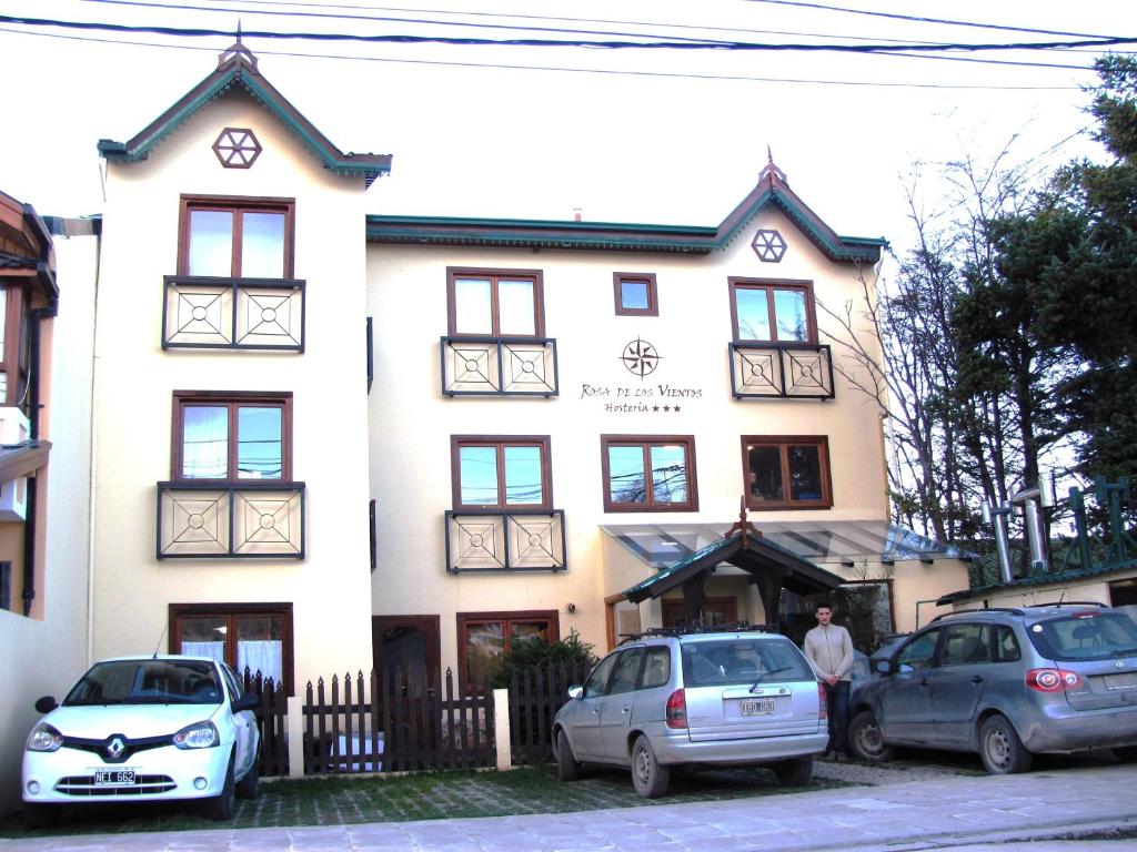 乌斯怀亚罗莎迪洛斯维恩托斯酒店的一座白色的建筑,前面有汽车停放