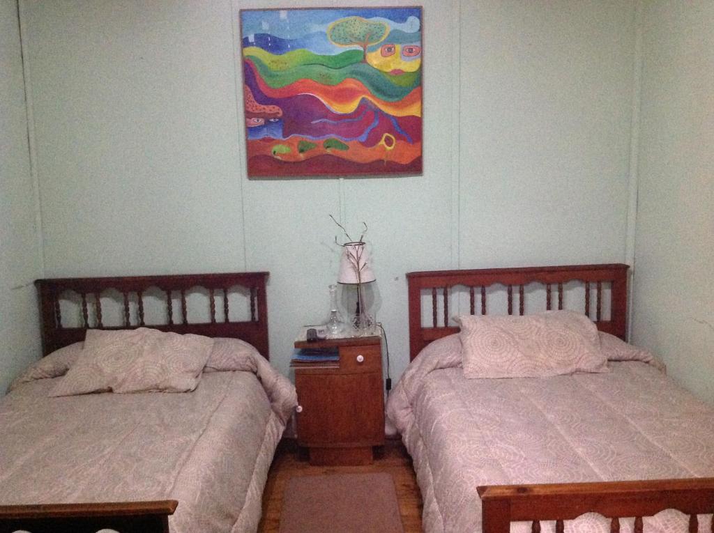 圣费尔南多雷诺阿旅馆的卧室内的两张床,墙上有绘画作品