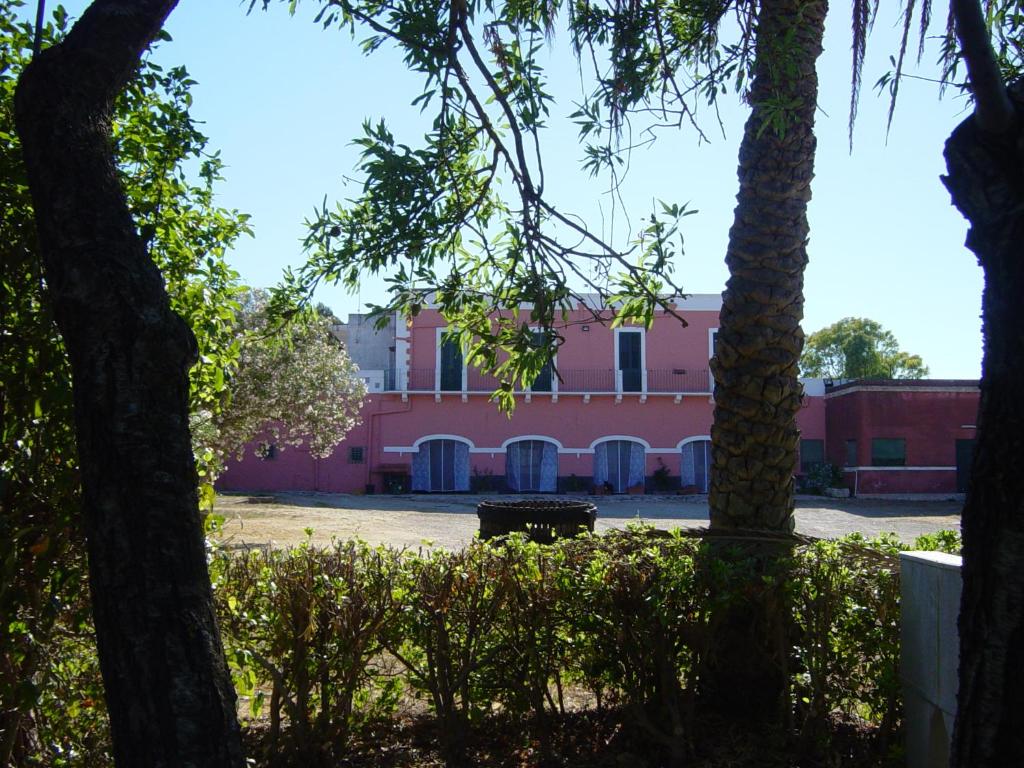梅萨涅Tenuta Argiano的公园中间的一座粉红色建筑,树木繁茂