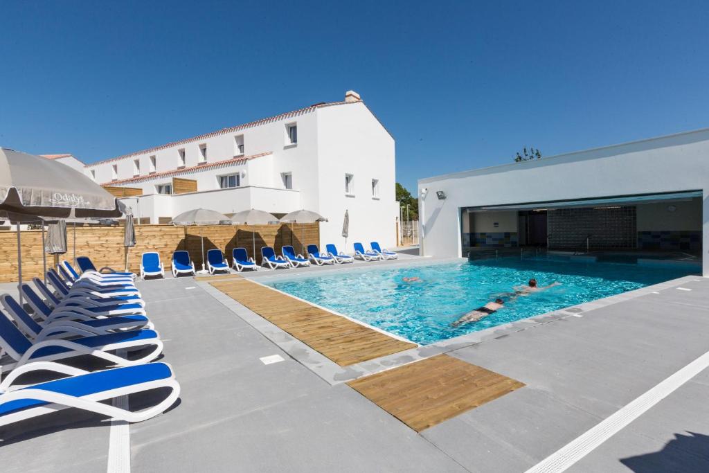 诺亚芒提亚Résidence Prestige Odalys Le Domaine des Pins的一座带躺椅的游泳池和一座建筑