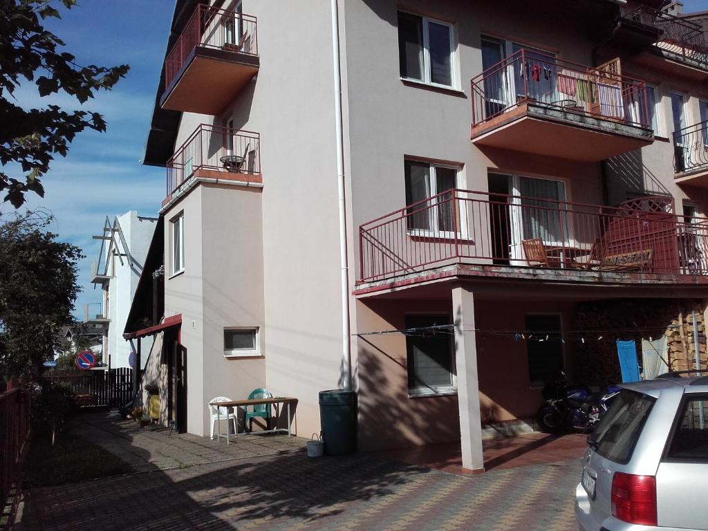 米兹多洛杰Pokoje u Bogusi的带阳台的建筑和旁边停车场